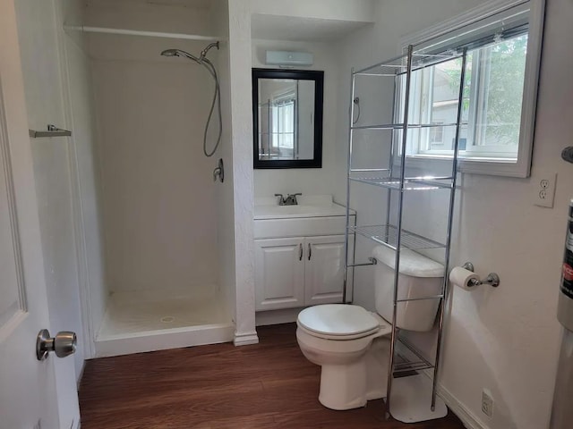 bathroom featuring hardwood / wood-style floors, vanity, toilet, and a shower