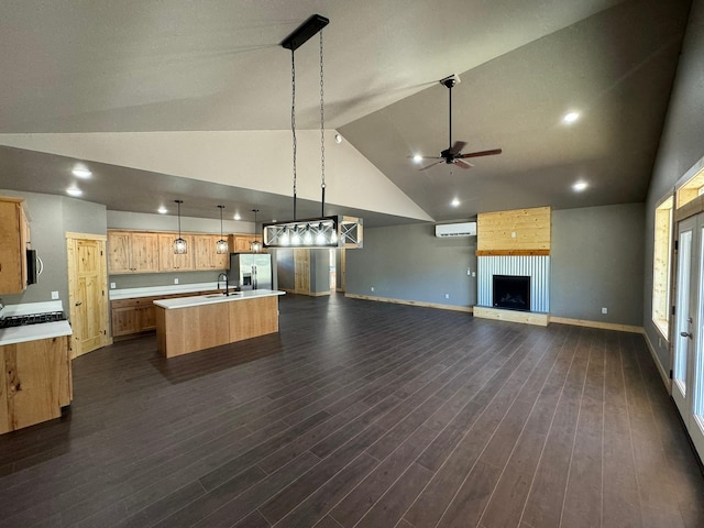 kitchen featuring ceiling fan, hanging light fixtures, stainless steel fridge with ice dispenser, an AC wall unit, and an island with sink