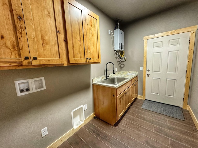 clothes washing area featuring hookup for a washing machine, water heater, sink, and cabinets