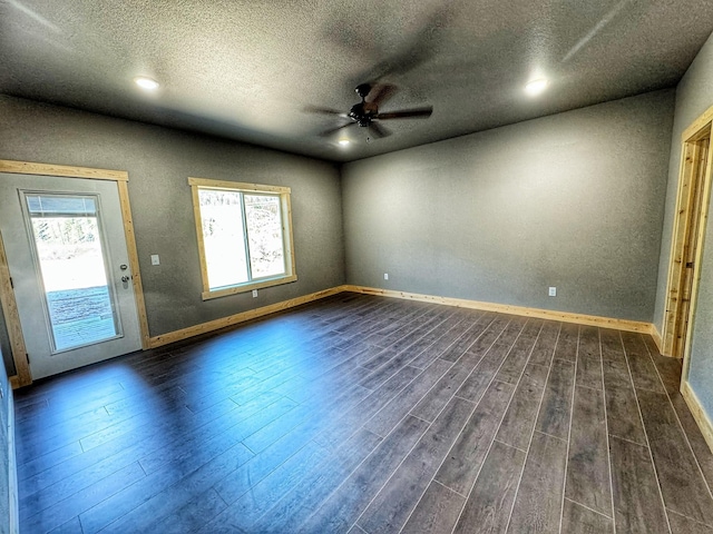 empty room featuring plenty of natural light, ceiling fan, and dark wood-type flooring