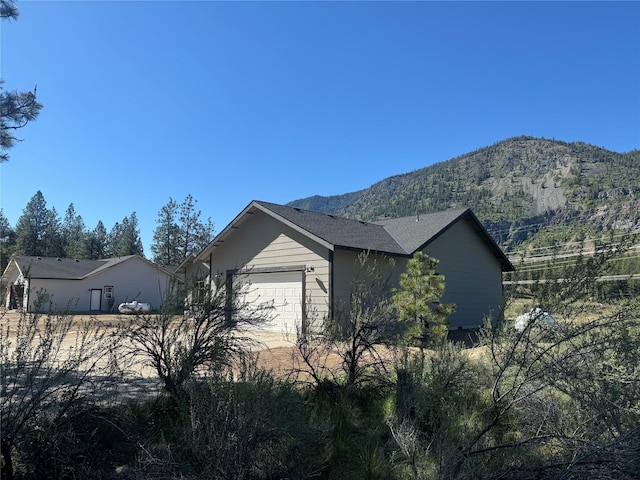 view of side of home with a mountain view and a garage