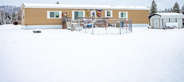 snow covered back of property featuring a storage shed