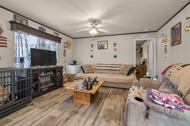 living room with ceiling fan, crown molding, and light wood-type flooring