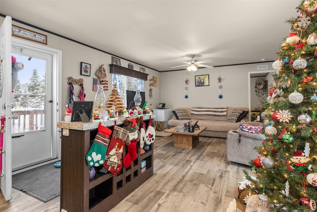 living room featuring light hardwood / wood-style floors, ceiling fan, and ornamental molding