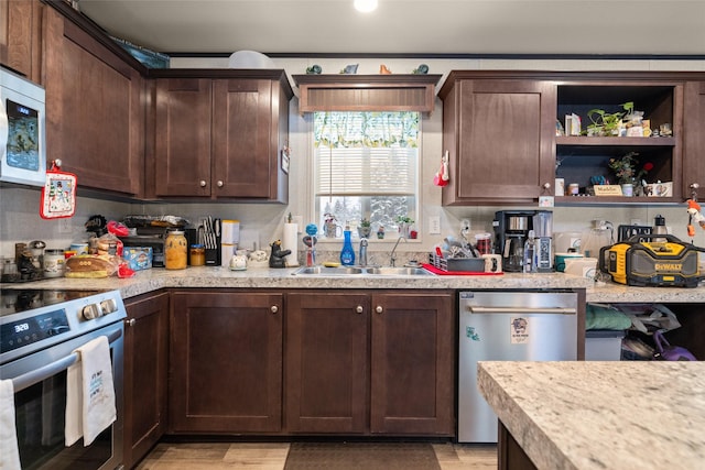 kitchen with dark brown cabinetry, stainless steel appliances, light stone counters, and sink