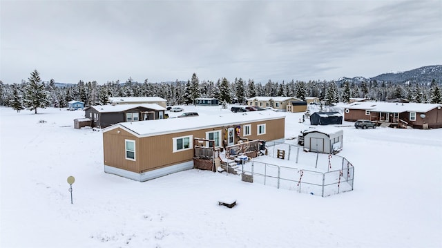 snow covered rear of property with a storage shed