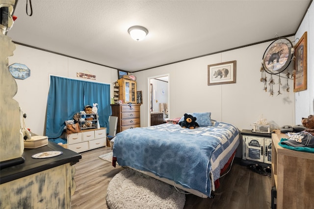 bedroom featuring a textured ceiling, light wood-type flooring, and ornamental molding