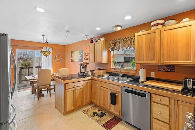 kitchen featuring kitchen peninsula, pendant lighting, stainless steel appliances, and sink