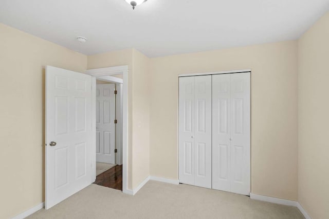 unfurnished bedroom with light colored carpet and a closet