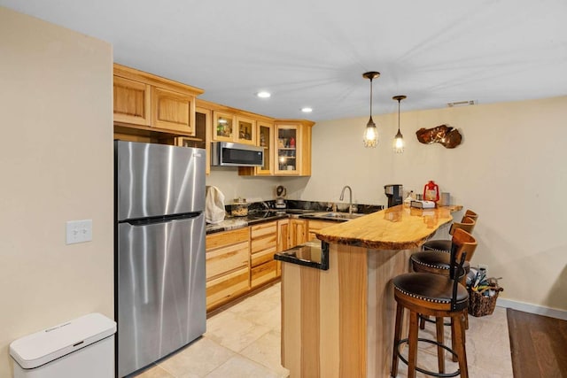 kitchen with pendant lighting, a kitchen breakfast bar, sink, kitchen peninsula, and stainless steel appliances