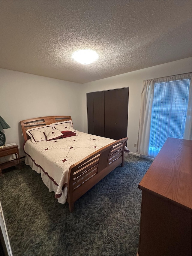 bedroom featuring a textured ceiling and dark colored carpet