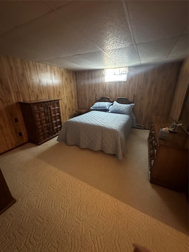 bedroom featuring carpet floors, a drop ceiling, and wooden walls