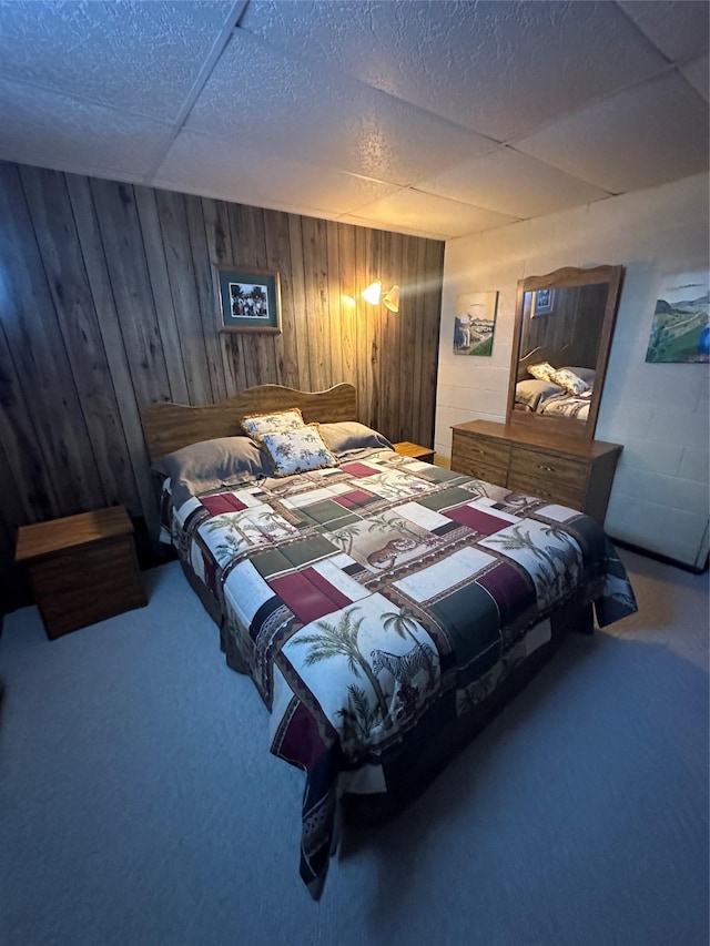 carpeted bedroom featuring wooden walls