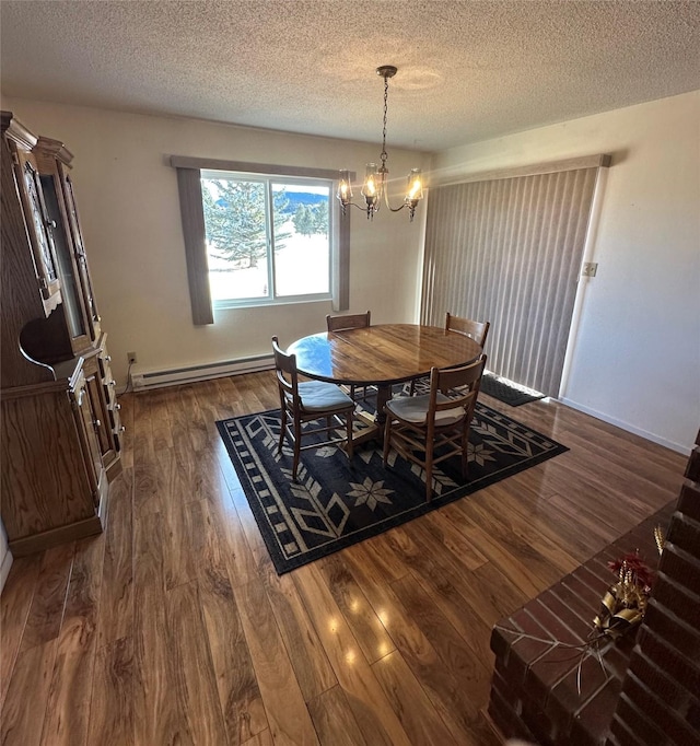 dining room featuring baseboard heating, dark wood-type flooring, a textured ceiling, and a notable chandelier