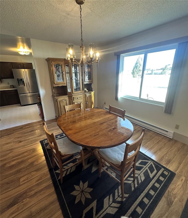 dining room with baseboard heating, a chandelier, a textured ceiling, and wood-type flooring