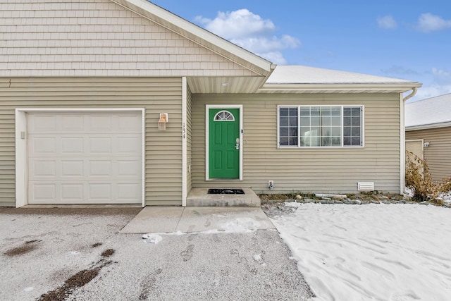 snow covered property entrance featuring a garage