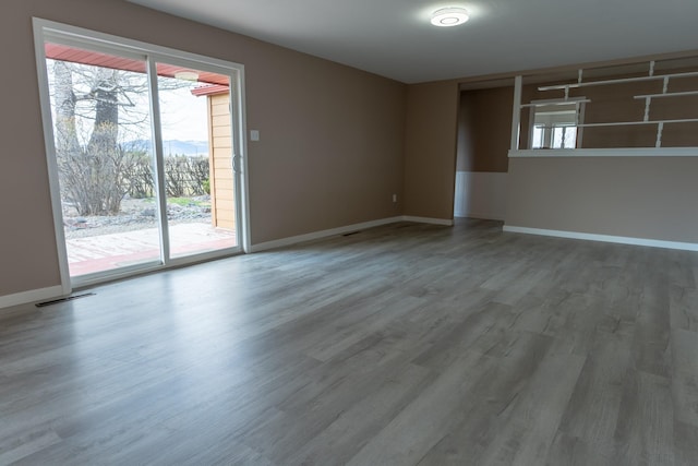 unfurnished room featuring wood finished floors, visible vents, and baseboards