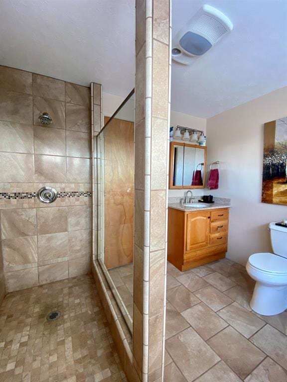 bathroom featuring a tile shower, vanity, and toilet