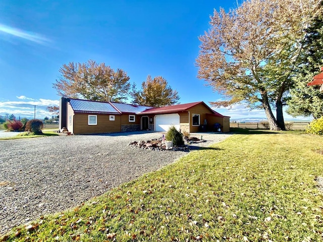 exterior space featuring gravel driveway, fence, a garage, a front yard, and metal roof