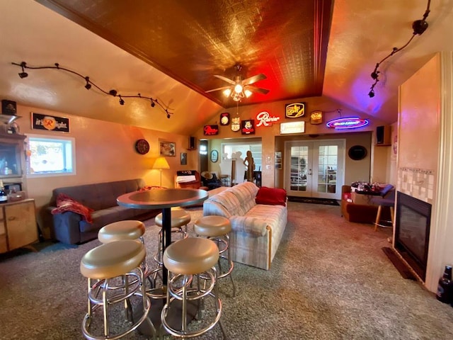 carpeted living room featuring a fireplace, ceiling fan, and lofted ceiling