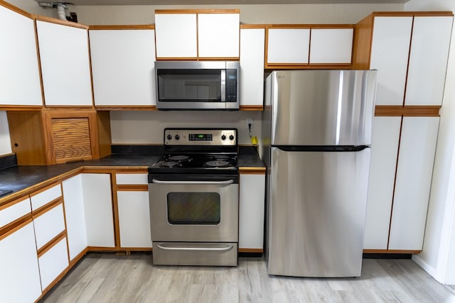 kitchen featuring light wood finished floors, stainless steel appliances, and white cabinets
