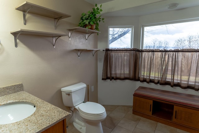 half bath featuring vanity, tile patterned flooring, and toilet