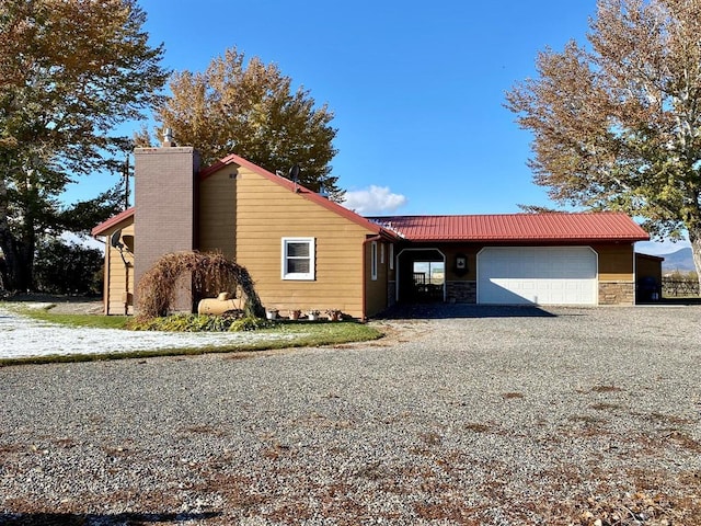 view of front of property featuring stone siding, a chimney, and a garage