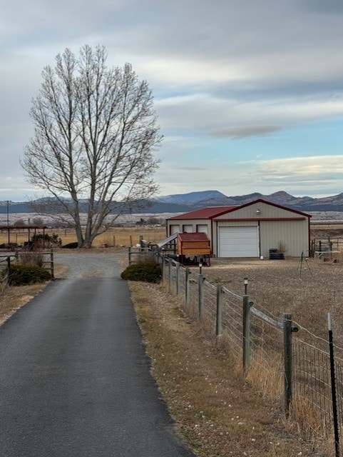 view of street featuring a mountain view, an outbuilding, and driveway