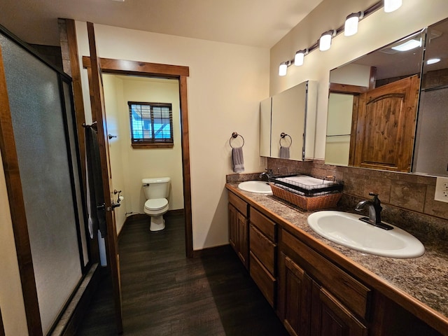 bathroom featuring hardwood / wood-style floors, toilet, decorative backsplash, a shower with door, and vanity