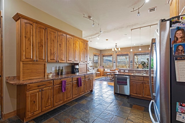 kitchen with pendant lighting, stone counters, sink, appliances with stainless steel finishes, and a notable chandelier