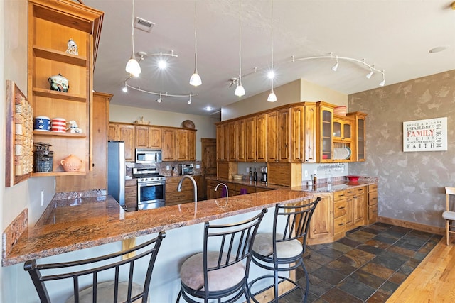 kitchen featuring kitchen peninsula, a kitchen breakfast bar, stainless steel appliances, and light stone countertops