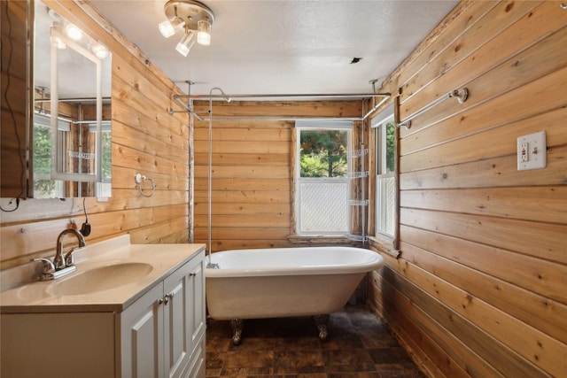 bathroom featuring wood walls, vanity, a bath, and a textured ceiling