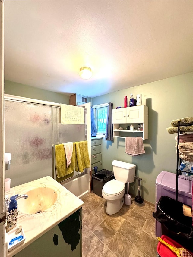 bathroom featuring toilet, vanity, baseboards, and a shower with shower door