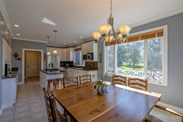 dining area with a chandelier, sink, crown molding, and light tile patterned flooring