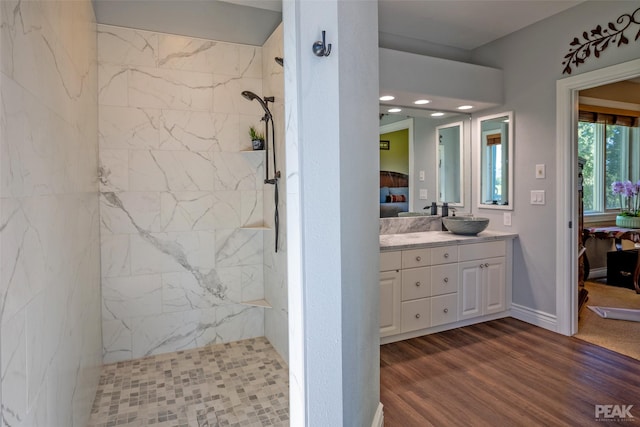 bathroom with wood-type flooring, vanity, and a tile shower