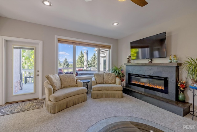 living room featuring carpet flooring, ceiling fan, a fireplace, and a wealth of natural light