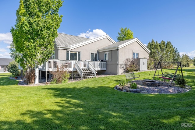 back of house with a deck, an outdoor fire pit, and a lawn