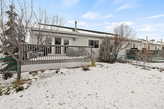 snow covered rear of property with a wooden deck