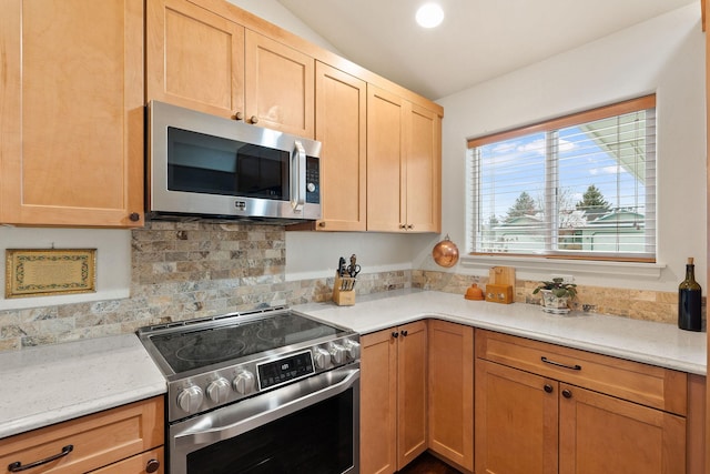 kitchen featuring stainless steel appliances, vaulted ceiling, and light brown cabinets