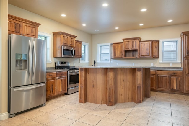 kitchen featuring a center island, light tile patterned flooring, stainless steel appliances, and stone countertops