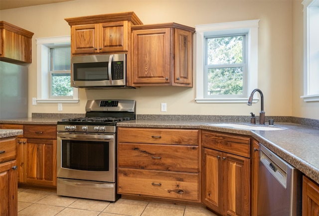 kitchen with sink, light tile patterned flooring, and appliances with stainless steel finishes