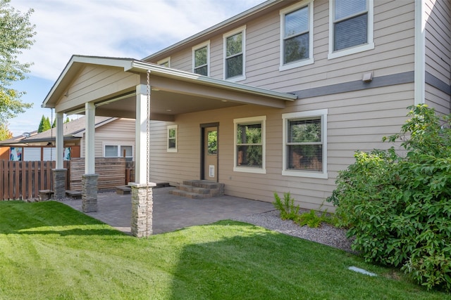 rear view of house featuring a lawn and a patio