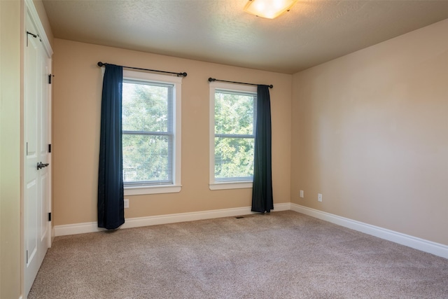 carpeted empty room with a textured ceiling