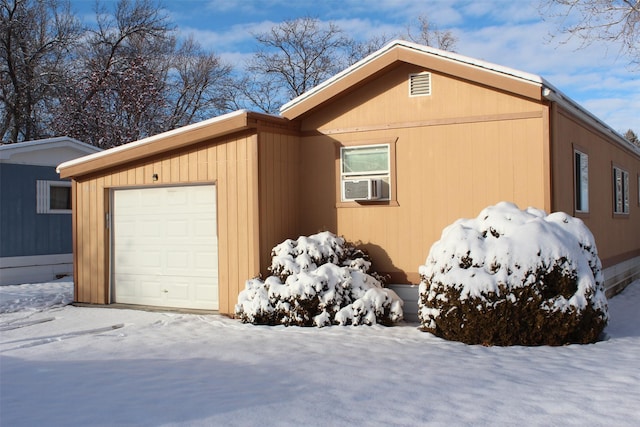 view of snowy exterior with cooling unit and a garage