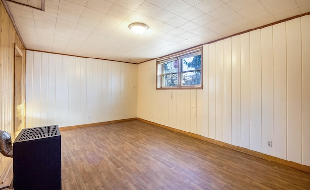 spare room with heating unit, crown molding, and hardwood / wood-style floors