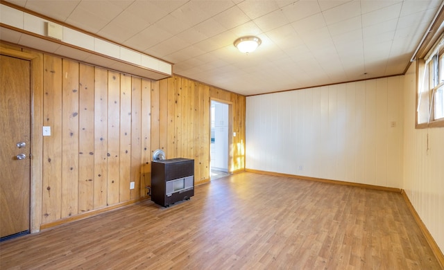 spare room featuring heating unit, wood walls, and light hardwood / wood-style flooring