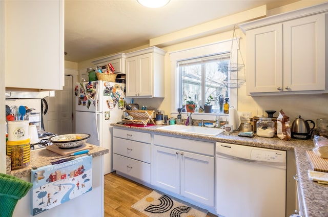 kitchen with white cabinetry, sink, light stone counters, white appliances, and light wood-type flooring