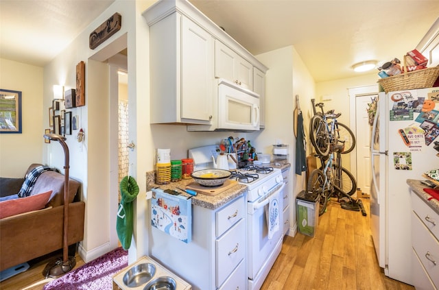 kitchen with white cabinets, white appliances, and light hardwood / wood-style flooring