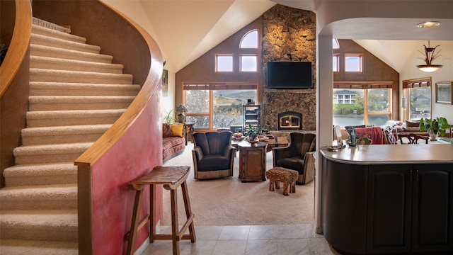 living room with a wealth of natural light, a fireplace, high vaulted ceiling, and light tile patterned floors