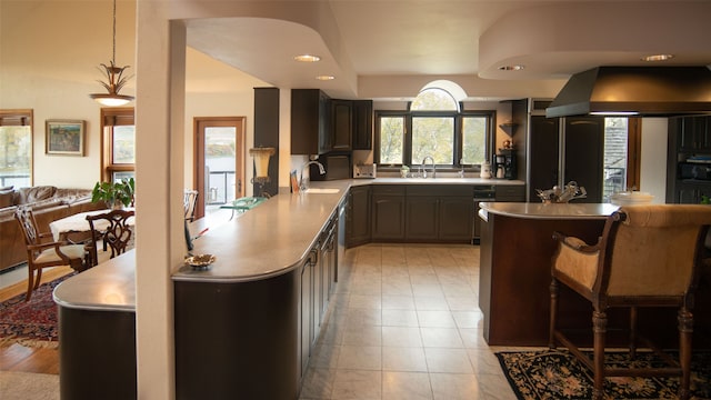 kitchen with a breakfast bar area, kitchen peninsula, island range hood, and sink